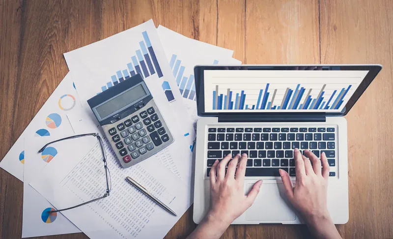 Laptop met grafieken, rekenmachine en financiële overzichten